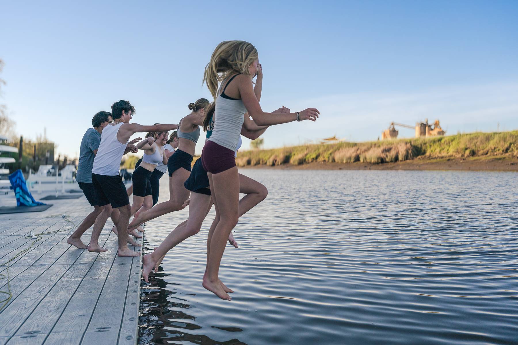 Rowing team leaping into the water together, full of energy