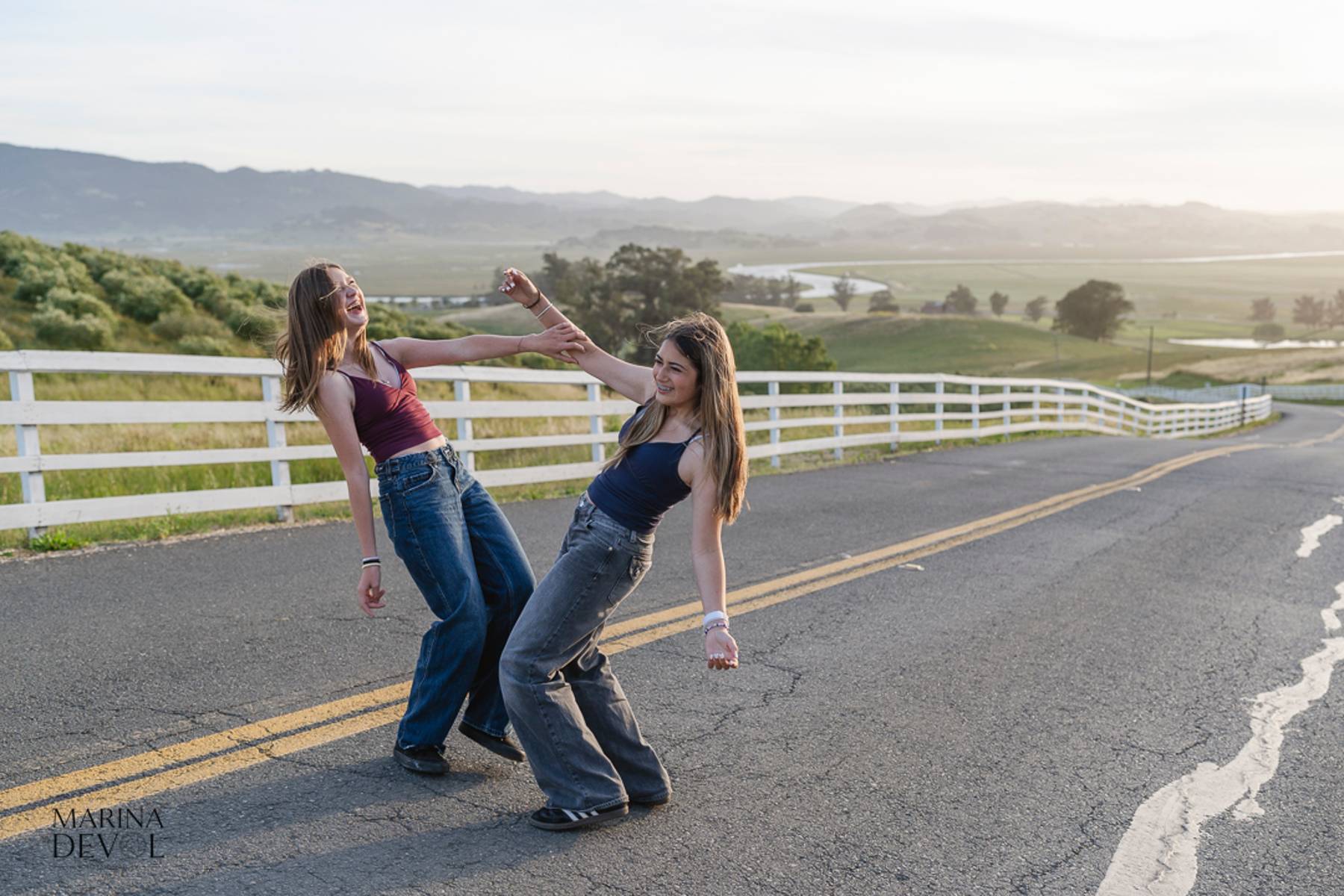 Two friends laughing and dancing on a country road