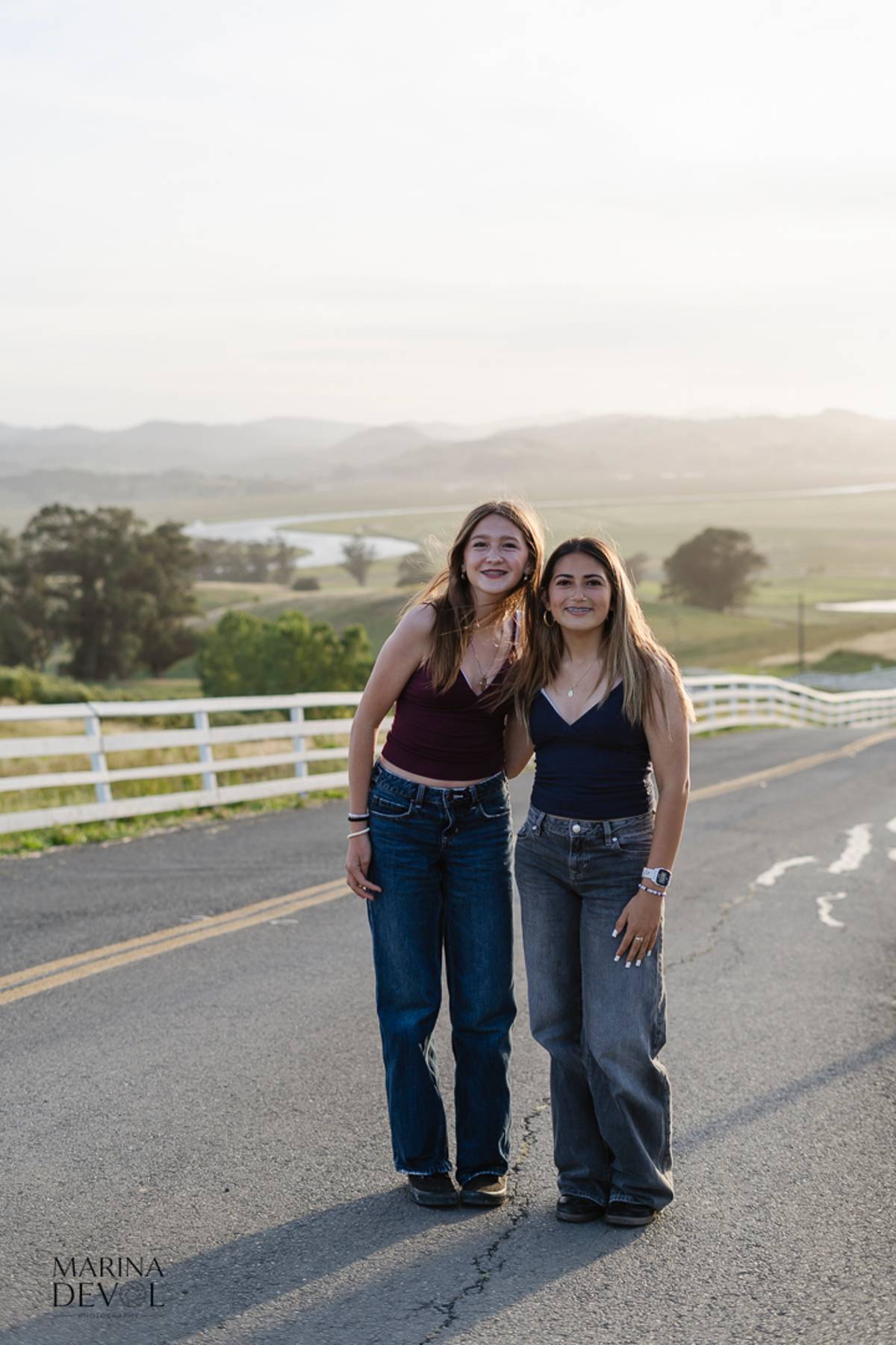 Two friends standing together on a country road, vertical portrait