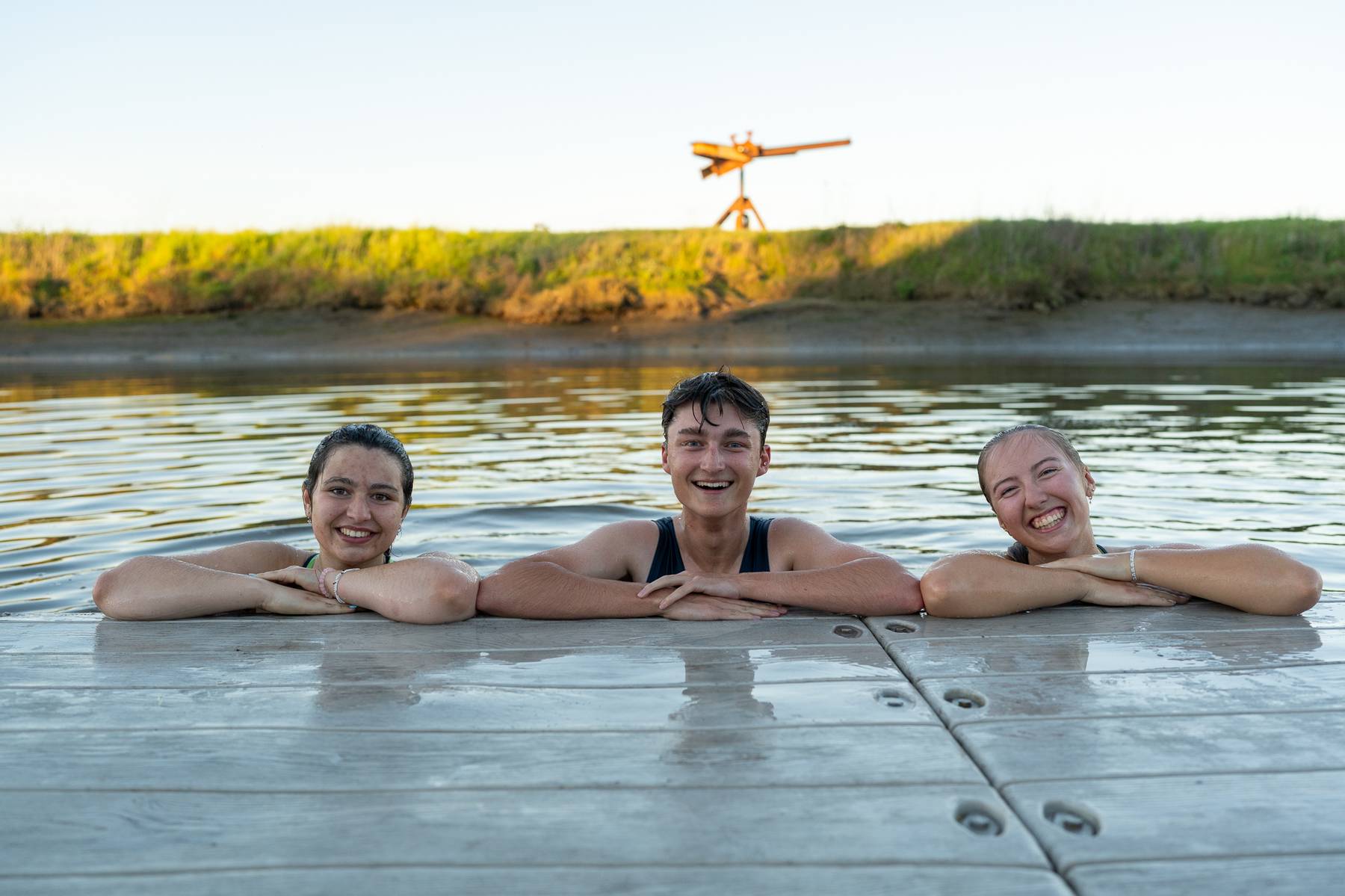Three teammates laughing while swimming